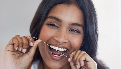 Woman smiling while flossing her teeth