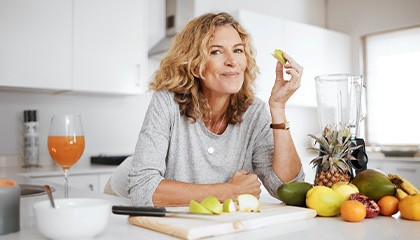 Woman leaning on kitchen counter eating fruit