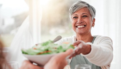 Woman smiling while grabbing bowl of salad