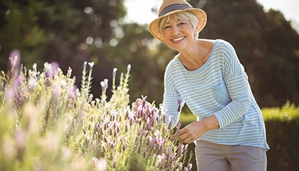 Woman in striped shirt and straw hat outside gardening