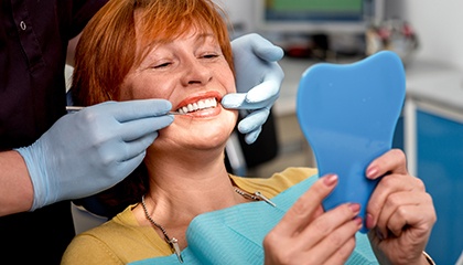 Woman with red hair in dental chair admiring reflection