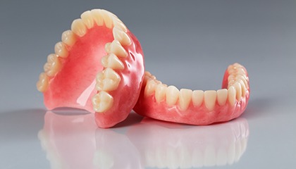 Complete set of dentures on reflective gray surface