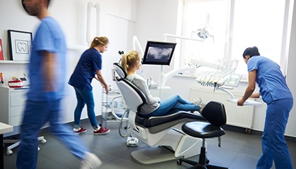 A blurred view of a woman surrounded by dentists at a dental practice