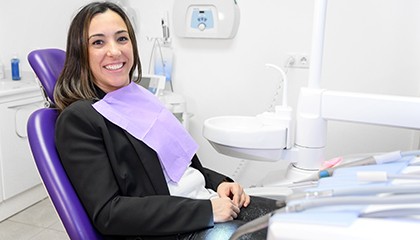 A smiling young woman sitting in a dentist’s chair and smiling at the camera